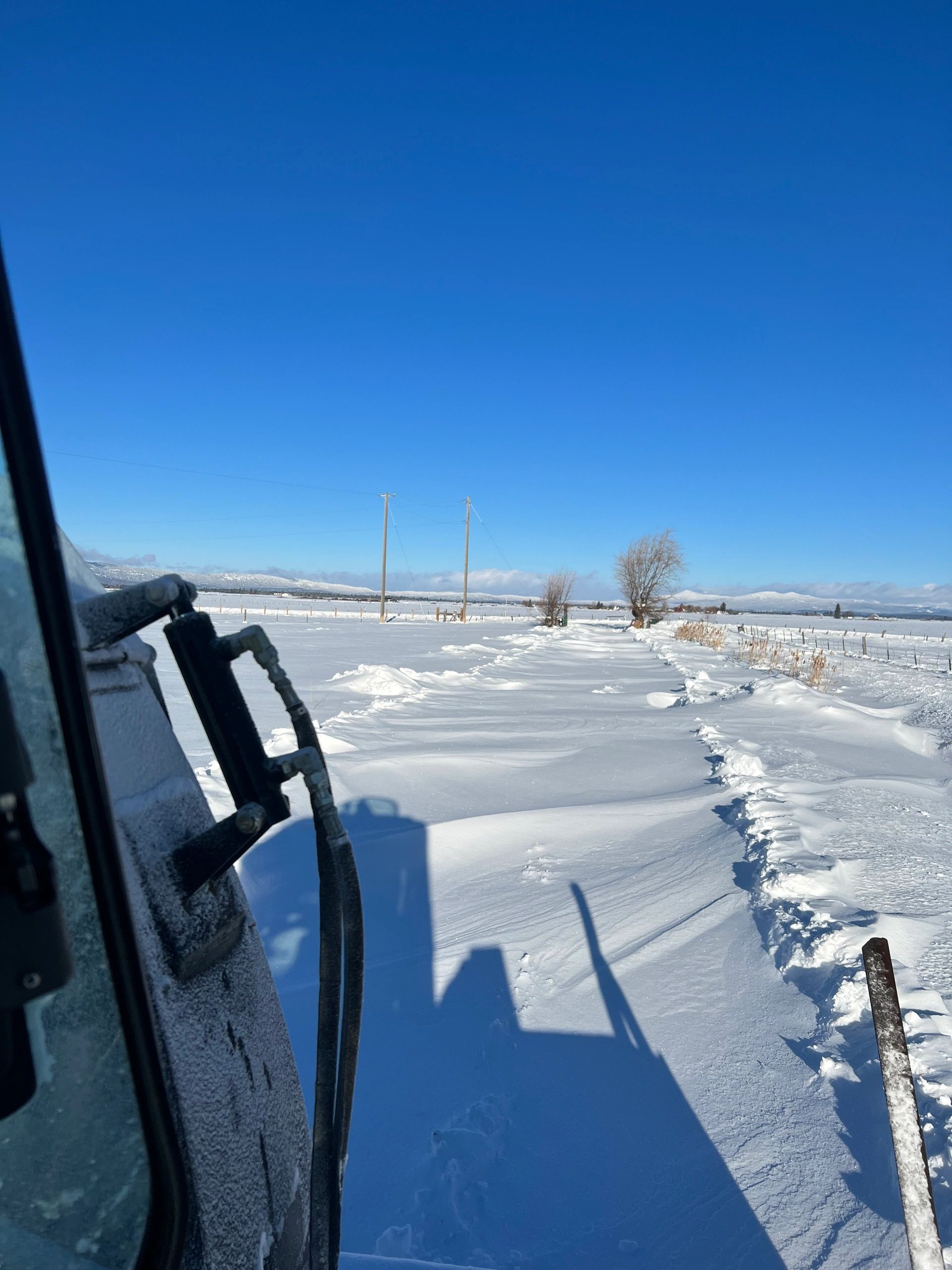 A snow-drifted Valley County road seen from a Brown Towing truck cab